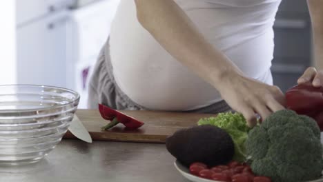 Cropped-shot-of-pregnant-woman-cutting-bell-pepper-on-table